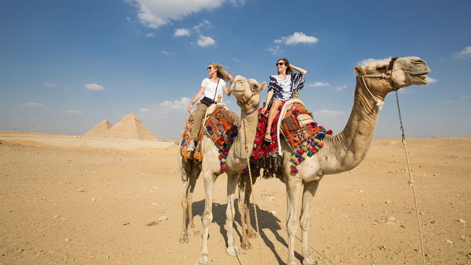 Egypt, Giza, Guests riding camels near the Great Pyramid of Giza