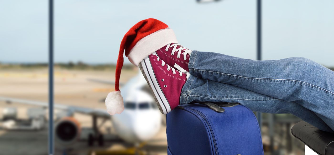 Image: Traveler with a Santa hat on his feet in an airport. (Photo via iStock / Getty Images Plus / Manuel Faba Ortega)